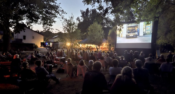 terrain sous les arbres avec des spectateurs et un film à l'écran
