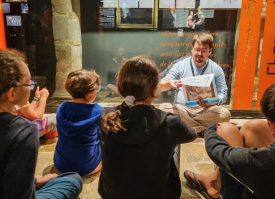 Un guide assis au sol parle à un groupe d'enfants