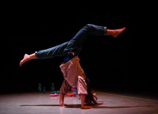 une circassienne fait une acrobatie main au sol, pied en l'aire