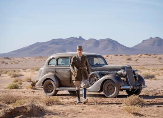 Charles De Gaulle marchant devant une voiture dans le désert