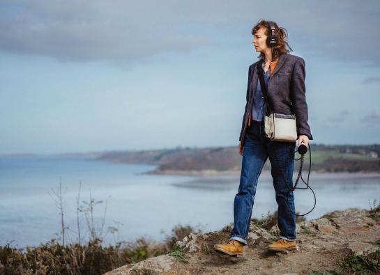 une journaliste marche au bord de la mer