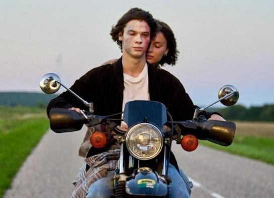 deux adolescents sur une moto au crépuscule