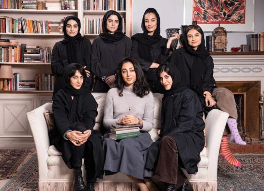 7 jeunes femmes dont 6 voilées sur un canapé avec une bibliothèque en fond