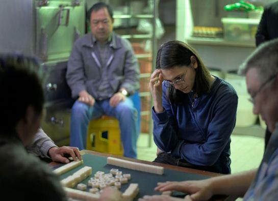 une jeune fille qui joue au mahjong avec de vieux chinois
