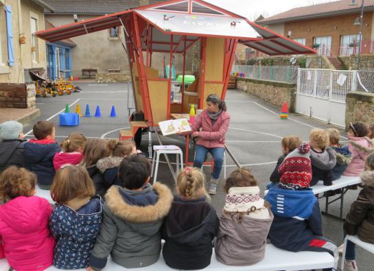 Une bibliothécaire lit une histoire à un groupe d'enfants devant l'Astromobile, bibliothèque ambulante
