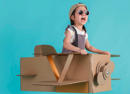 Photo d'une petite fille qui joue dans une maquette d'avion en carton